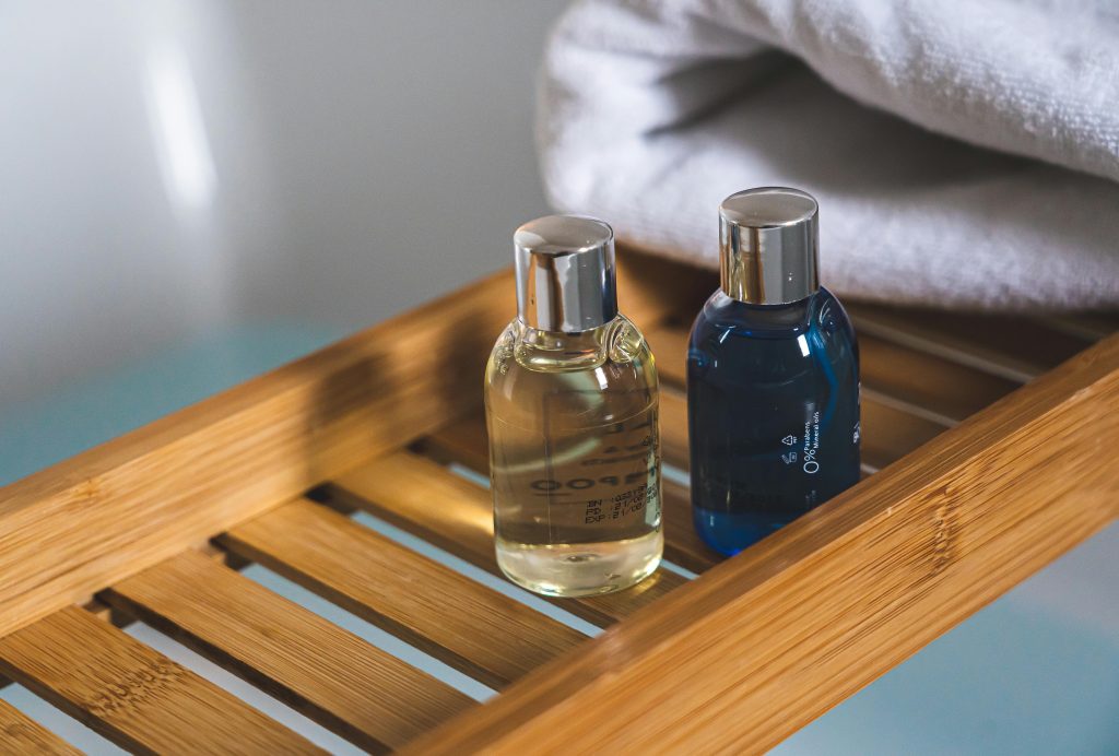 Two elegant toiletries bottles on a bamboo tray in a serene bathroom setting.